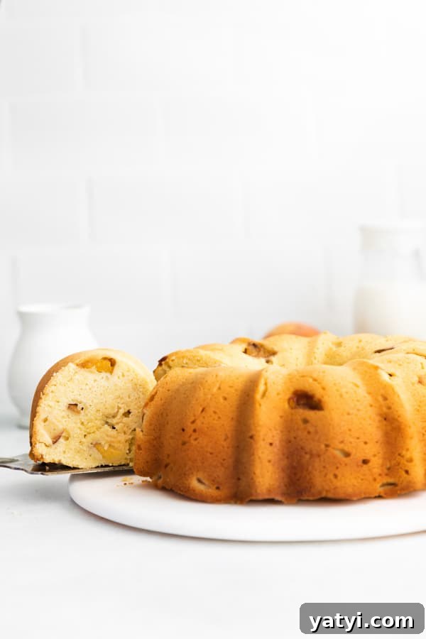 Glazed Peach Bundt Cake Recipe with Fresh Summer Peaches 4 Peach Bundt Cake with a slice being take out of the cake.