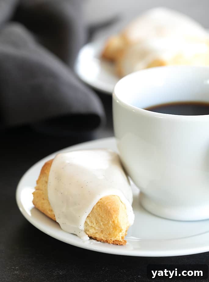 Gluten-Free Vanilla Scones Inspired by Starbucks 2 A close up of an iced vanilla scone with a cup of coffee on a plate