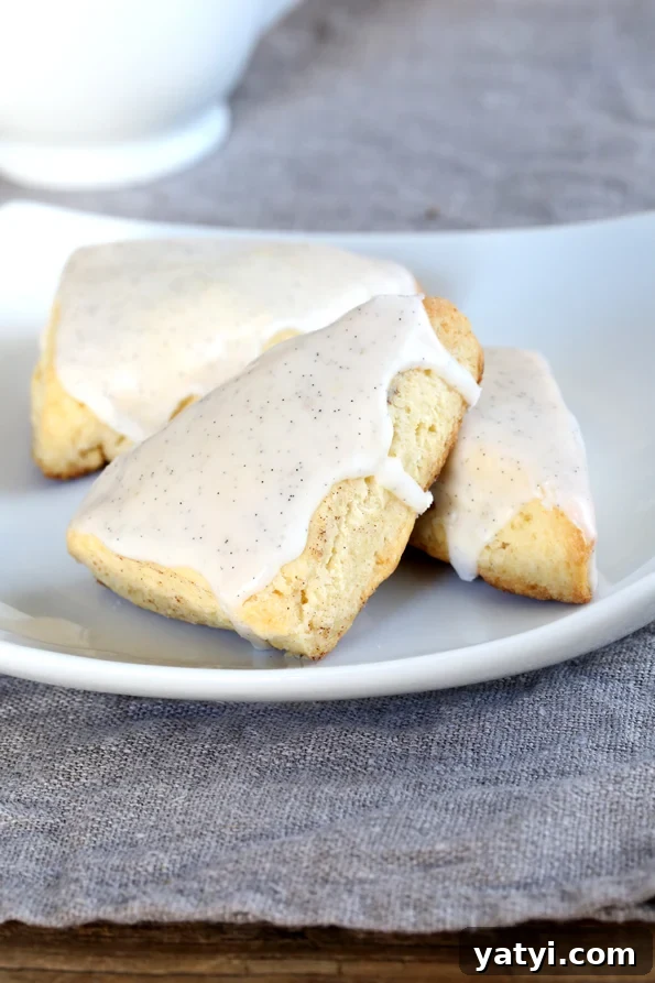 Starbucks-Style Gluten Free Petite Vanilla Bean Scones Three small vanilla scones with white icing on a plate.