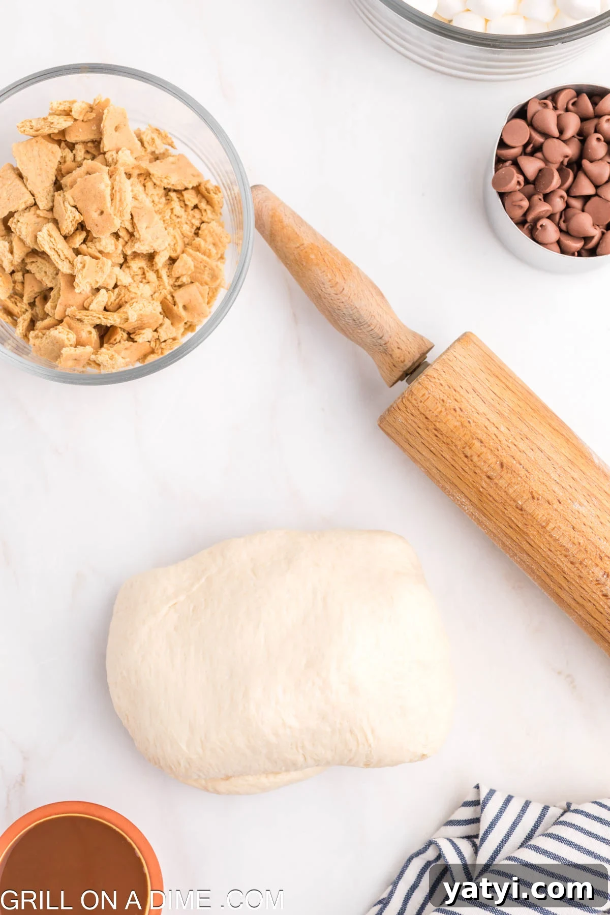 Pizza Dough with a rolling pin and crushed graham crackers in a bowl