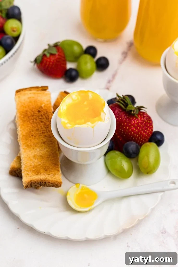 Perfect Soft-Boiled Eggs in an Air Fryer 2 Lightly cooked soft boiled egg with toast and fruit on a white plate.