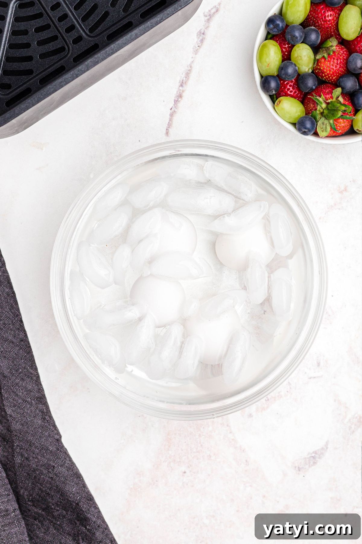 Perfect Soft-Boiled Eggs in an Air Fryer 5 Four eggs in a clear glass bowl in an ice bath.
