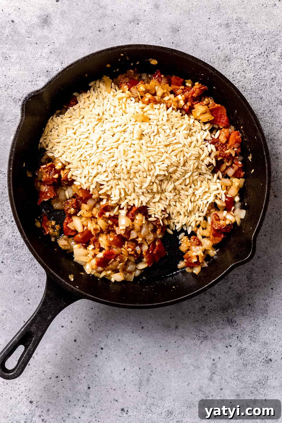 Tuscan Chicken Orzo with Sun-Dried Tomatoes and Spinach 6 Dried orzo being added to the pan.