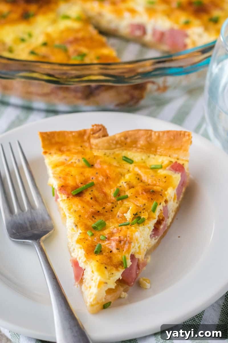 Brunch is a snap when you make this Easy Ham and Cheese Quiche! Simply prep your pie crust, pour in the filling and bake. It's practically fool-proof! slice of quiche on a plate with a fork