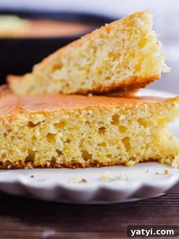 Two pieces of cornbread are on a fluted plate.