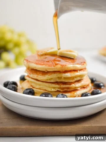 Maple Syrup is being poured over a stack of sourdough discard pancakes.