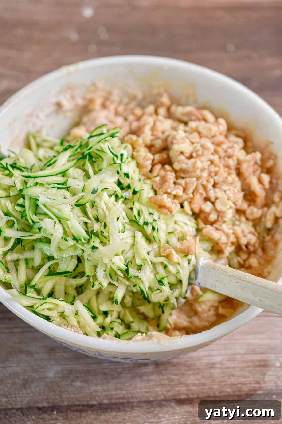 Sourdough Discard Zucchini Muffins Recipe (Quick & Moist) 8 The shredded zucchini and walnuts are added to the bowl.