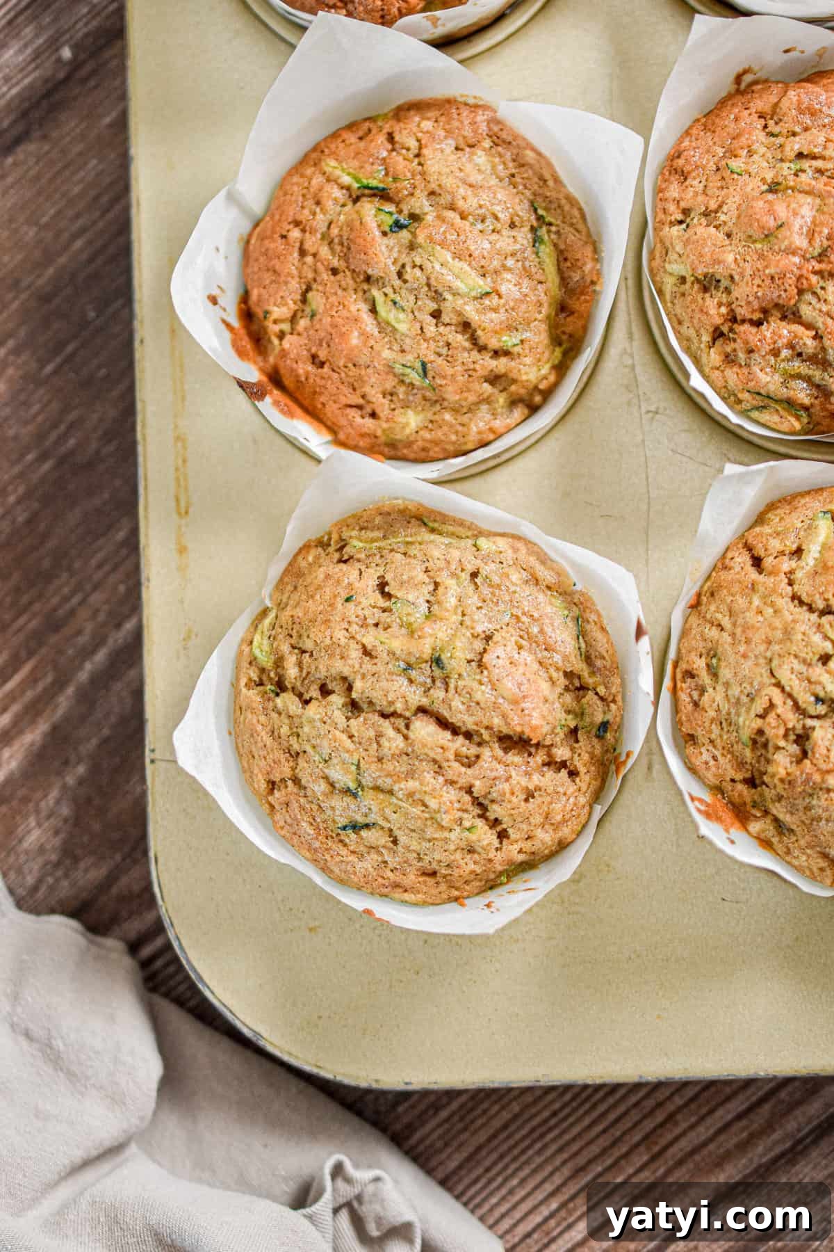 Sourdough Discard Zucchini Muffins Recipe (Quick & Moist) 10 The sourdough discard zucchini muffins are in muffin liners in a gold muffin tin.