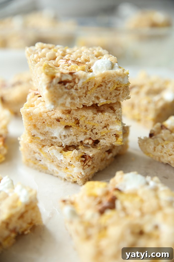 Three square sweet and salty Rice Krispies treats stacked on top of each other with cut rice crispy treats surrounding the stack.