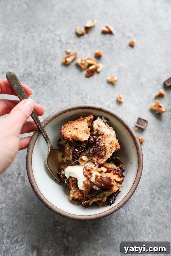 Gluten- and Dairy-Free Chocolate Chip Banana Bread Pudding 7 hand holding spoonful of dairy-free banana bread pudding with chocolate chips and walnuts