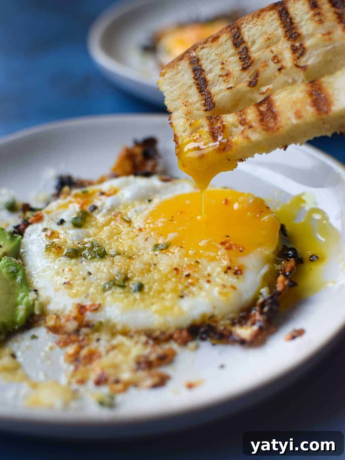 Fried egg with bread being dunked in a runny yolk.