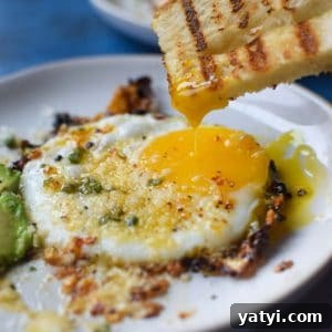 Fried egg with bread being dunked in a runny yolk.