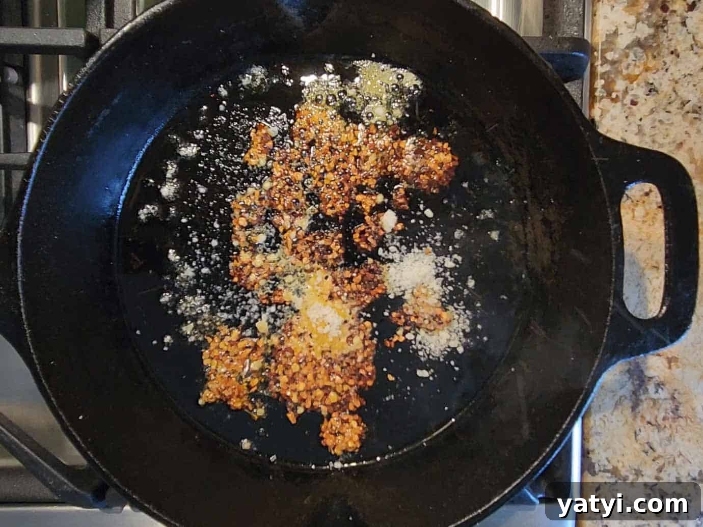 Chili crisp and parmesan cheese added to a hot skillet.