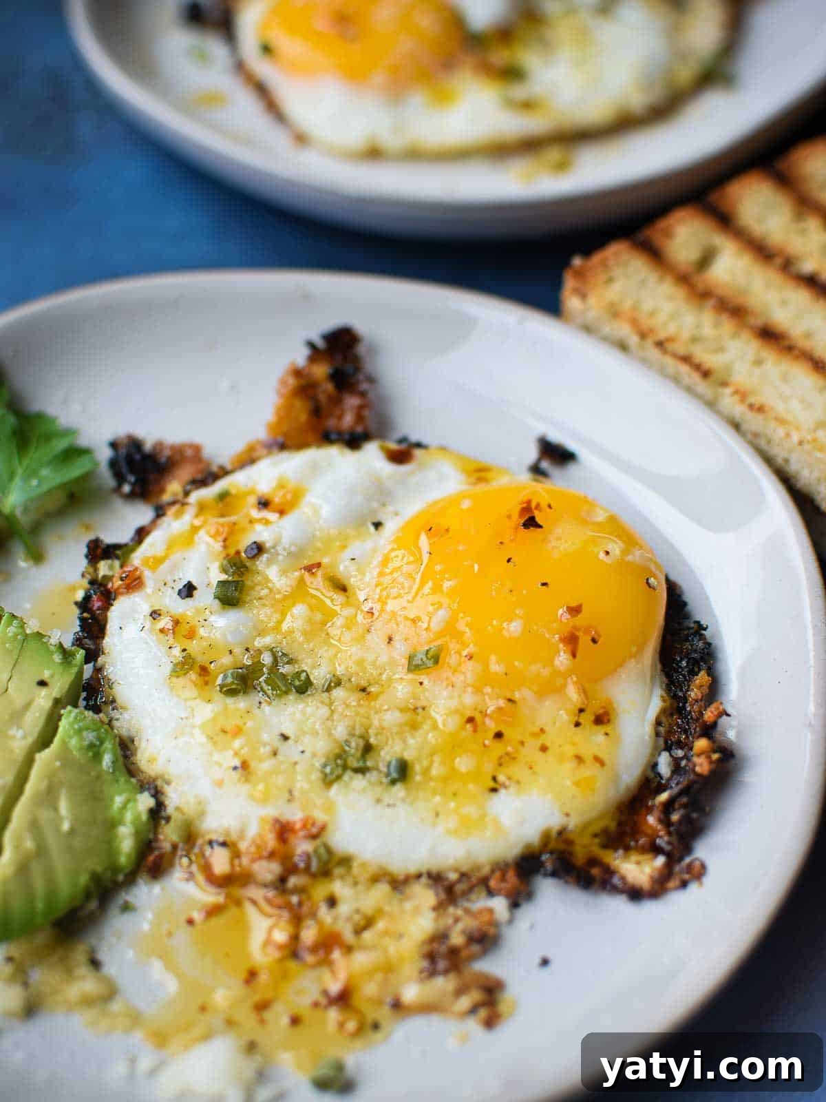 Fried egg on a white plate with chili crisp on top.
