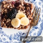 Blackberry Baked Oatmeal Recipe for Summer Brunch 12 Blackberry baked oatmeal on a blue plate with banana slices and blackberries.