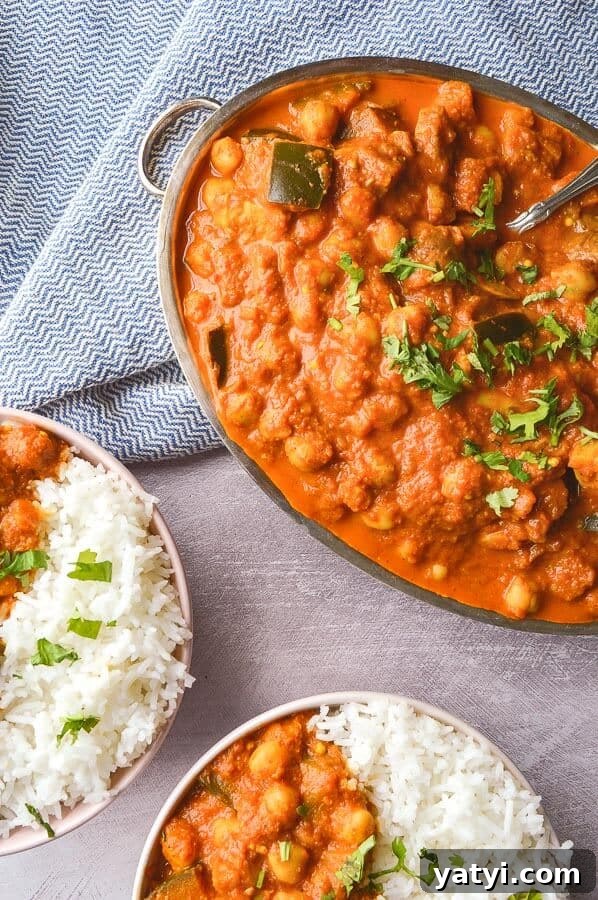 One-Pot Vegan Tikka Masala Recipe for Flavorful Dinner 3 A large silver dish of an orange gravy with garbanzo beans and two smaller dishes of it with rice on the side