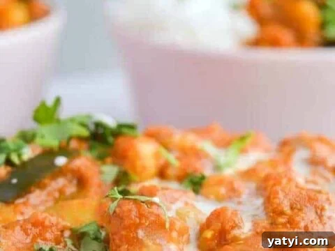 A closeup of orange curry sauce with chickpeas, and two bowls of it with rice in the background