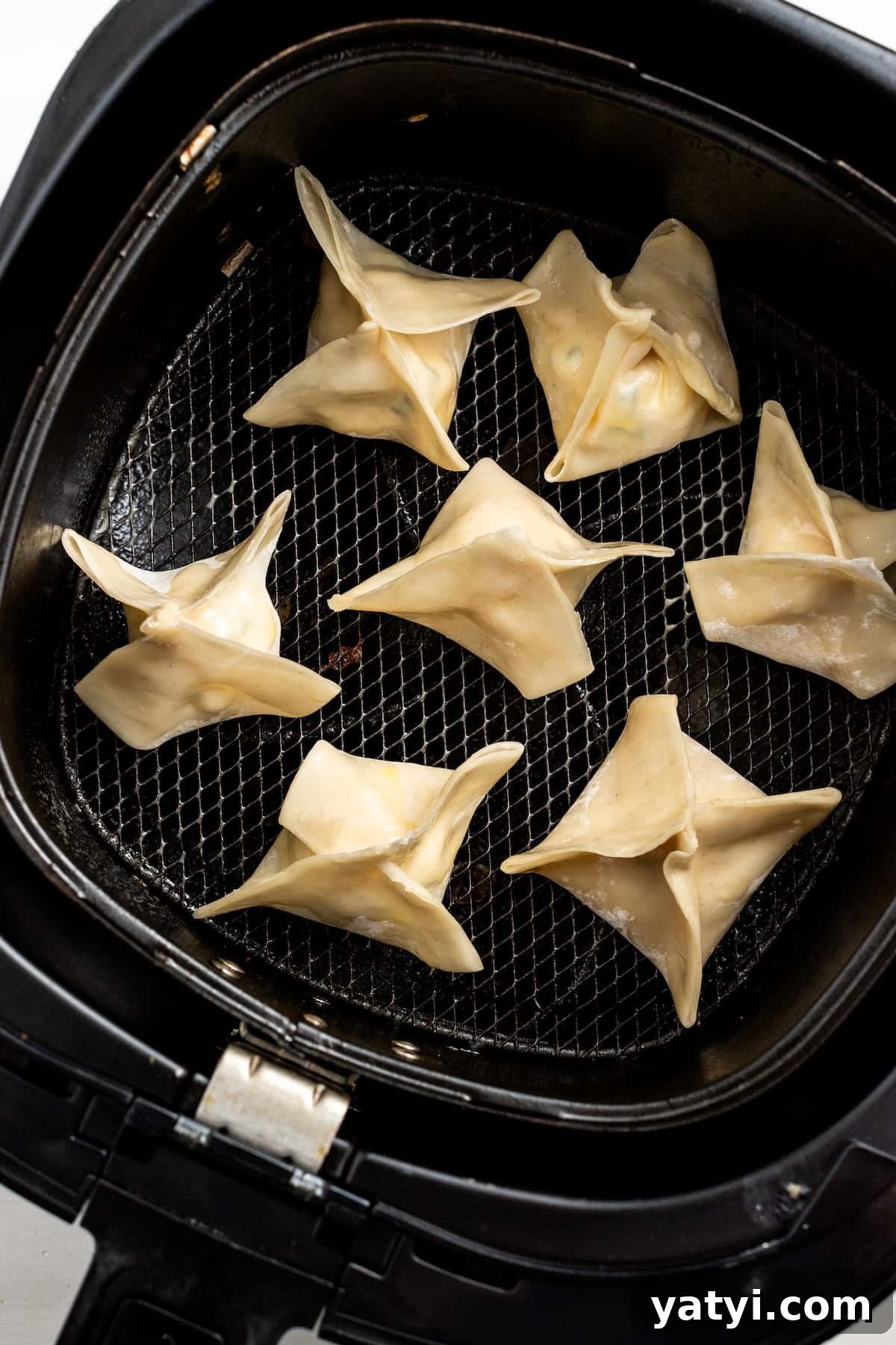 Crispy Air Fryer Crab Rangoon: Quick Seafood Appetizer Recipe 3 Uncooked crab rangoon in the basket of an air fryer.