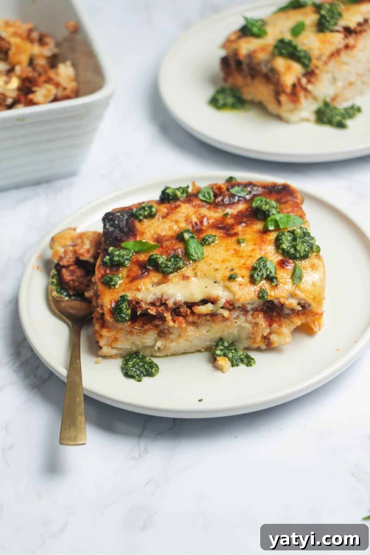 Bolognese Rice Bake on a small white plate, with another plate of the bake in the background.