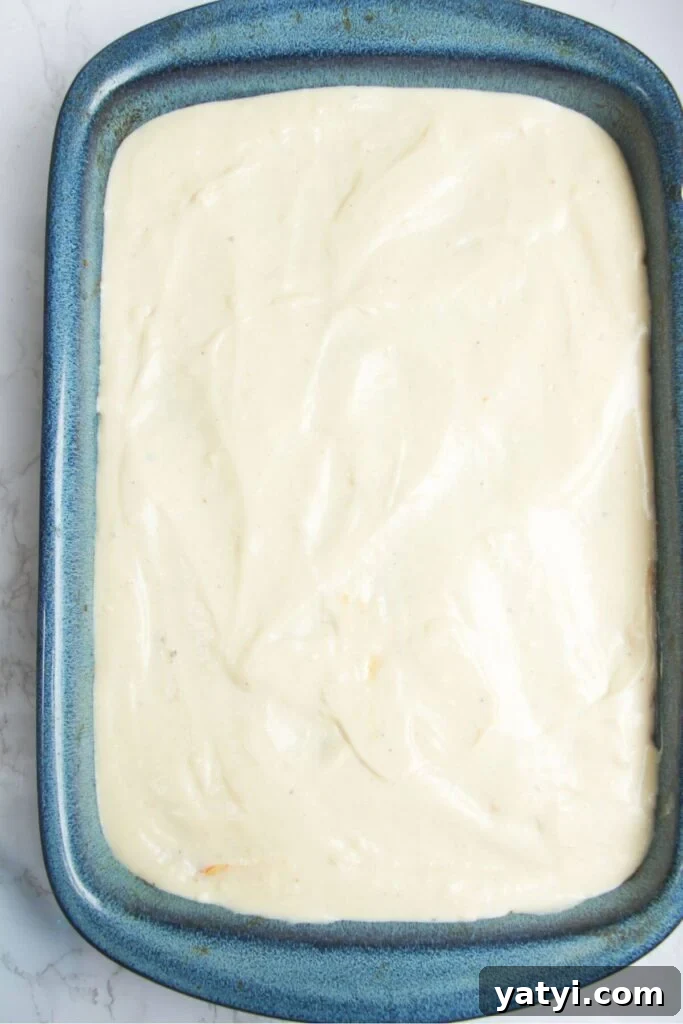 Cheesy bechamel sauce in a large blue oven dish.