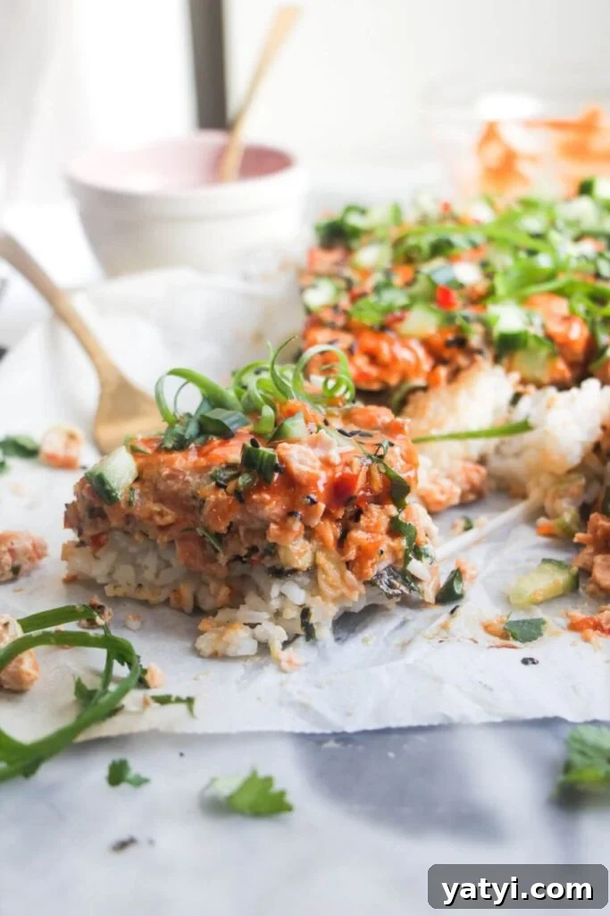 Close up of a piece of salmon sushi bake, with the rest of the bake in the background.