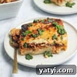 Bolognese Rice Bake on a small white plate, with another plate of the bake in the background.