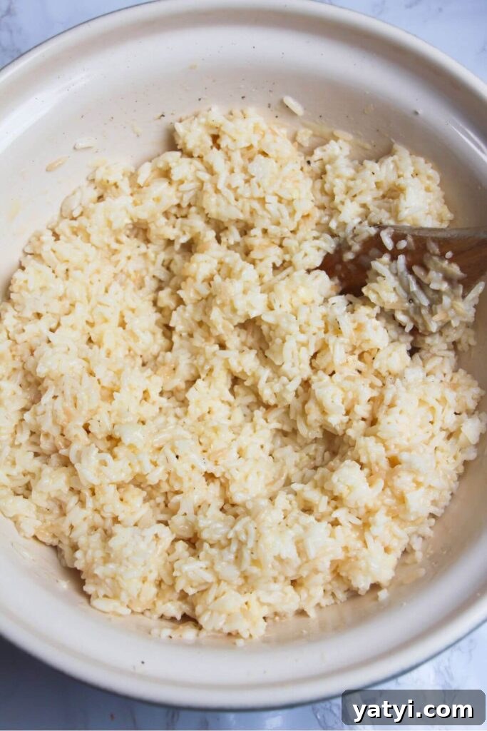 Rice mixed with egg and grated cheese in a large bowl.