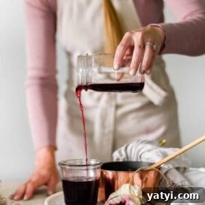 Homemade Elderberry Syrup Recipe (Updated) 7 Homemade Elderberry Syrup being poured into jar for colds and flus.