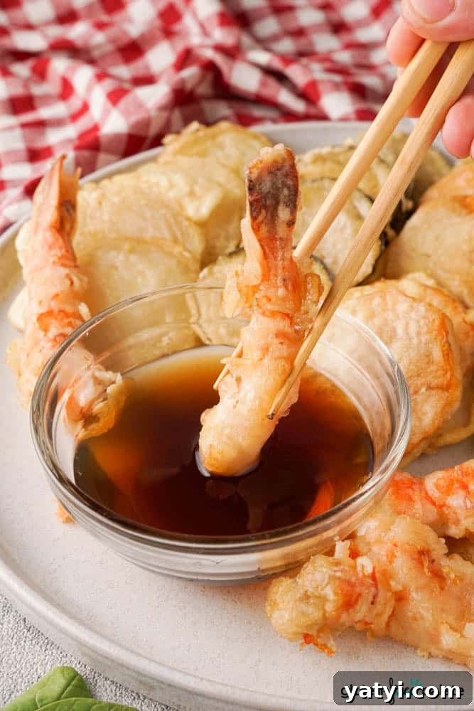 Crispy Gluten-Free Tempura Recipe: Light, Crunchy & Vegan-Friendly 8 Gluten-free tempura prawn being dipped into the dipping sauce.