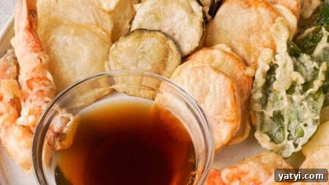 Gluten-free tempura on a white serving plate with a dipping sauce.
