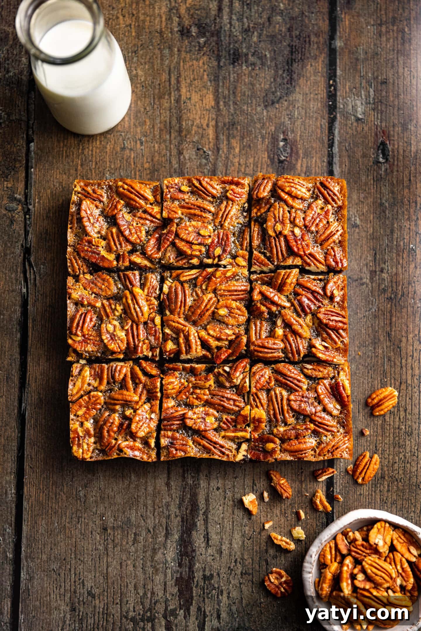 Decadent Pecan Pie Brownies Recipe — Gooey Chocolate Pecan Bars 2 Pecan Pie Brownies next to a bowl of pecans and a glass of milk