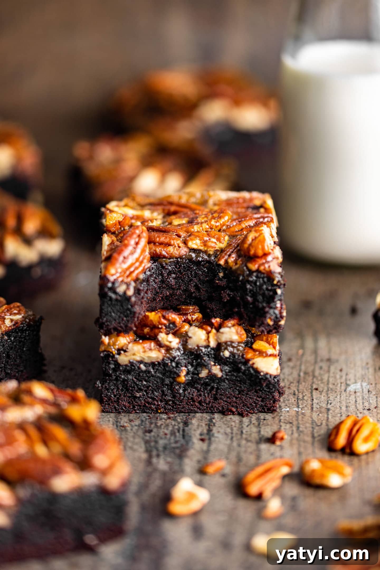 Decadent Pecan Pie Brownies Recipe — Gooey Chocolate Pecan Bars 7 Pecan Pie Brownies stacked on top of each other with a bite missing