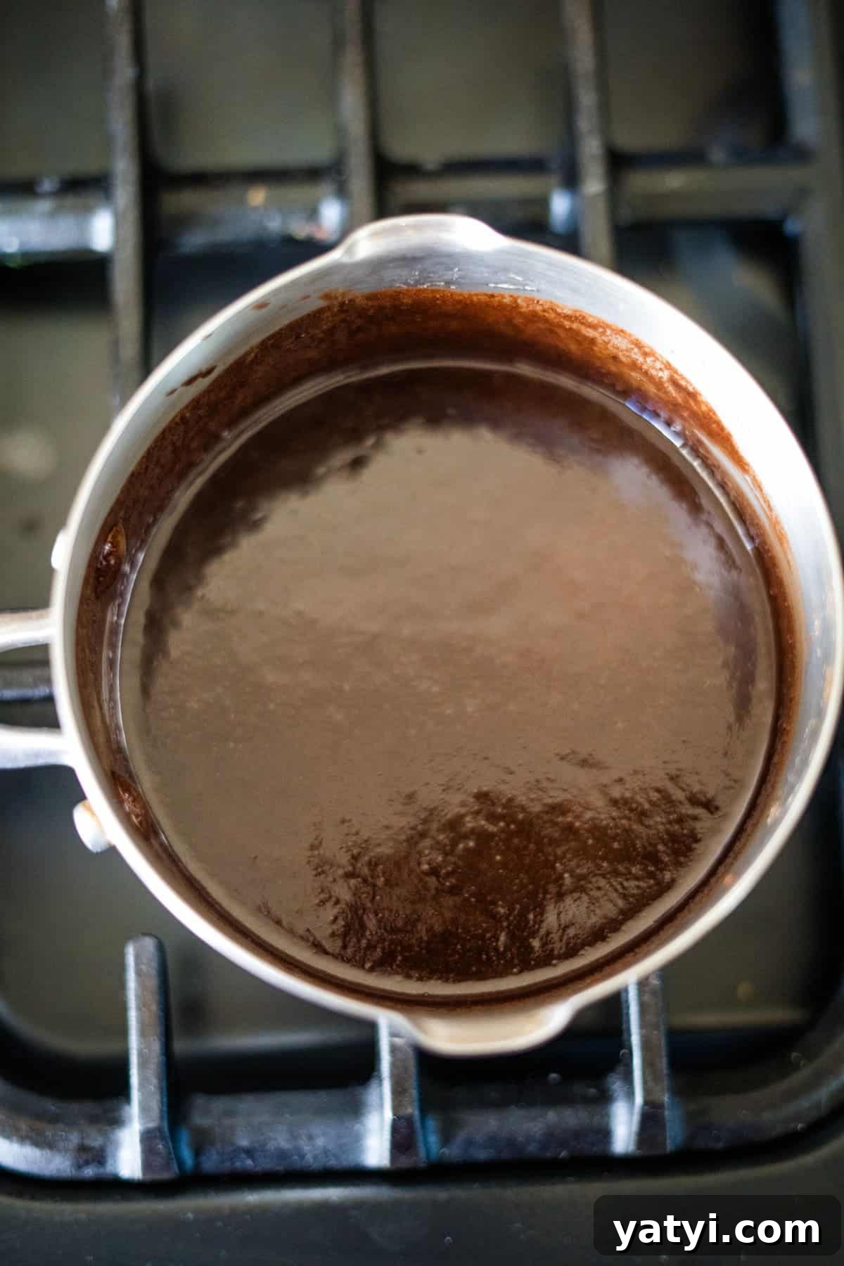 Keto Chocolate Pecan Torte Recipe – Low-Carb Dessert Delight 5 A saucepan with thick chocolate sauce simmers on the stove, reminiscent of the rich layers found in a decadent pecan torte.