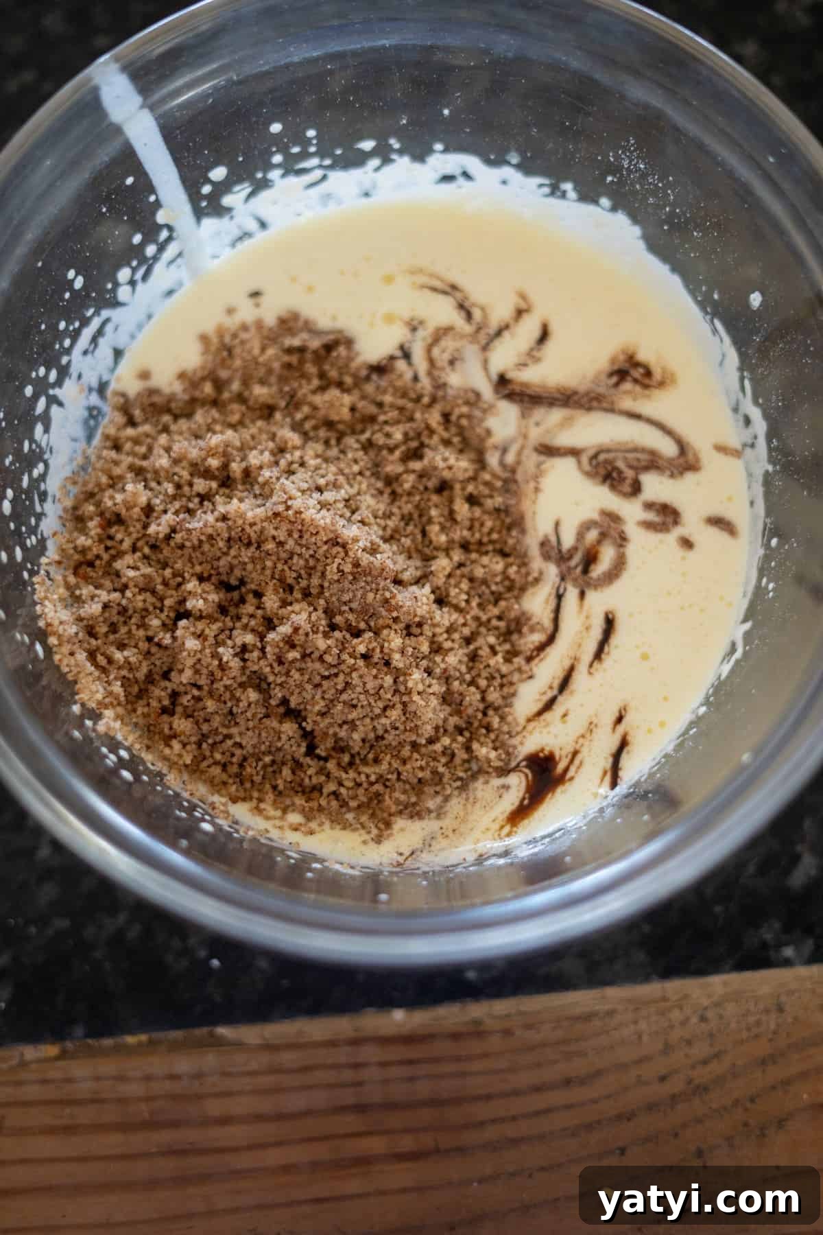 Keto Chocolate Pecan Torte Recipe – Low-Carb Dessert Delight 7 A glass bowl with cake batter, brown sugar, and vanilla extract being mixed together for a delightful pecan torte.