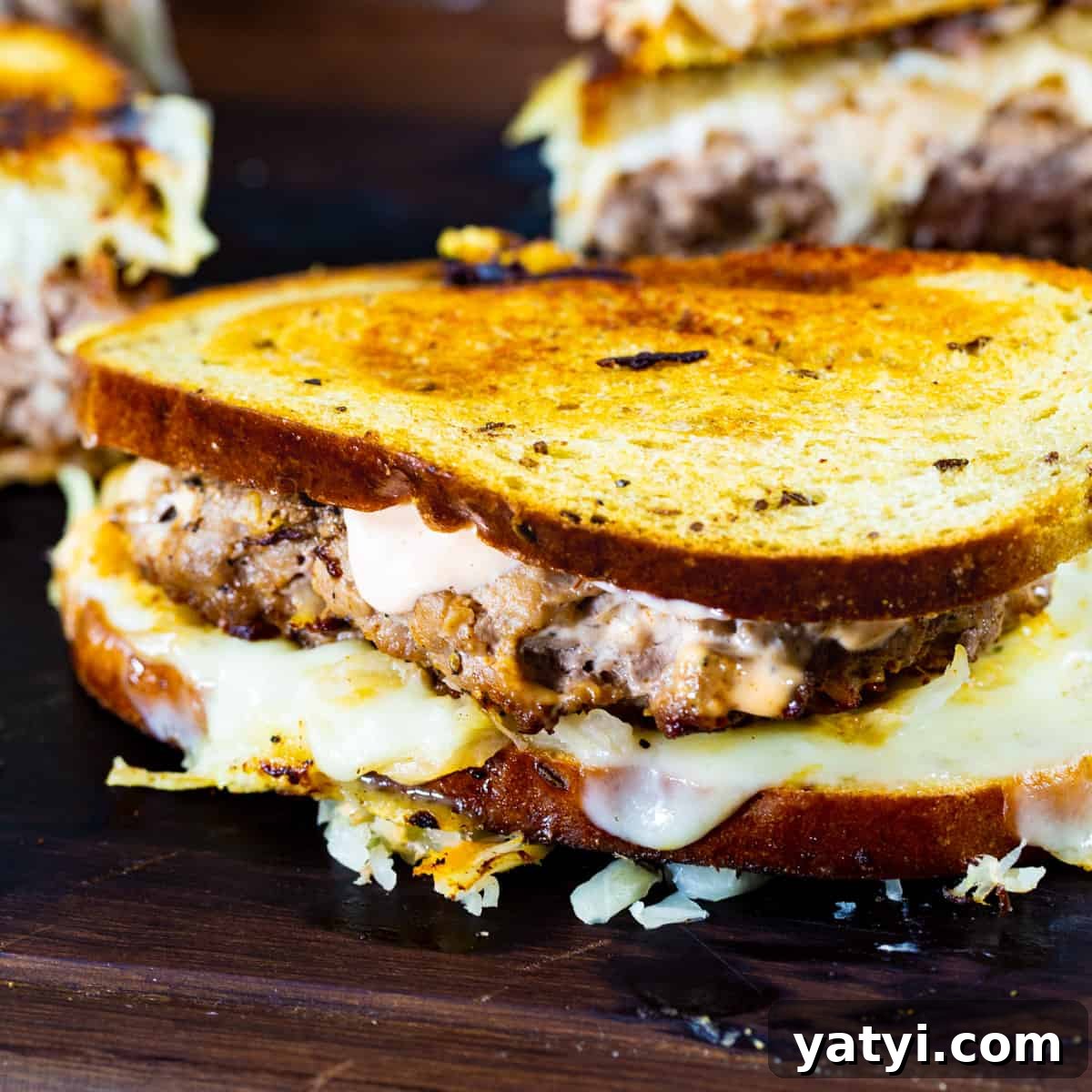 Turkey Reuben Patty Melt Recipe — Tangy Thousand Island Turkey Burgers 2 Turkey Burger Reuben Patty Melts on a cutting board.