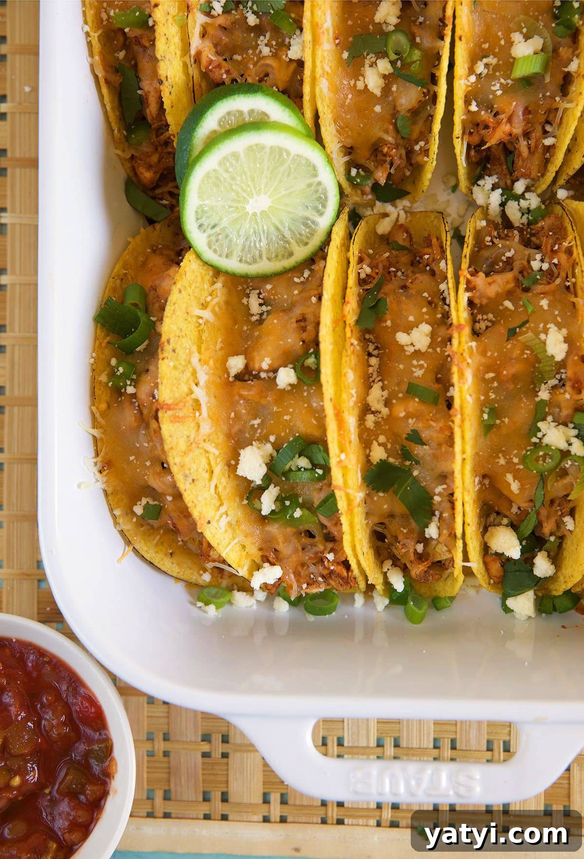 Oven-Baked Chicken Tacos with Crispy Seasoned Filling 2 Chicken tacos are lined up and filling a white casserole dish.