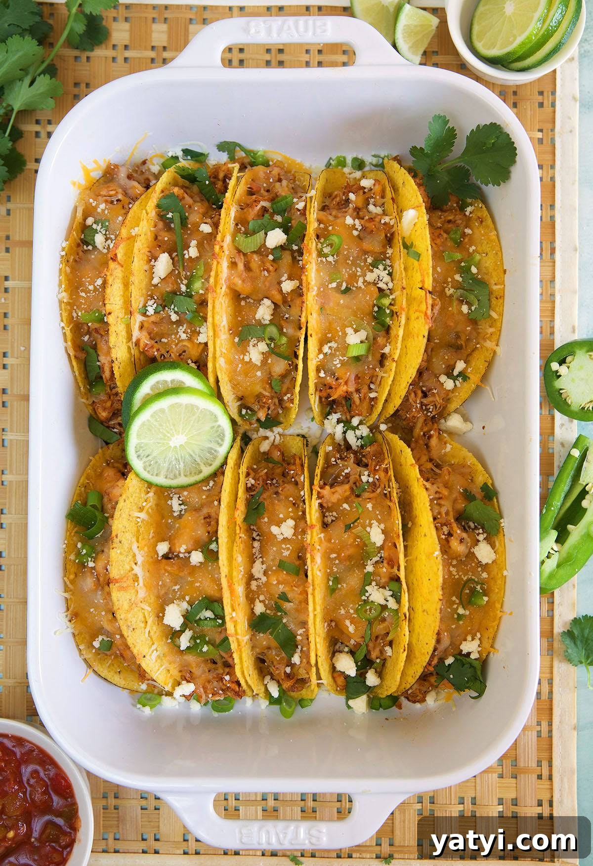 Oven-Baked Chicken Tacos with Crispy Seasoned Filling 4 Ten tacos are placed in a large baking dish.
