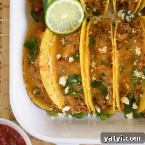Oven-Baked Chicken Tacos with Crispy Seasoned Filling 7 Chicken tacos are lined up and filling a white casserole dish.
