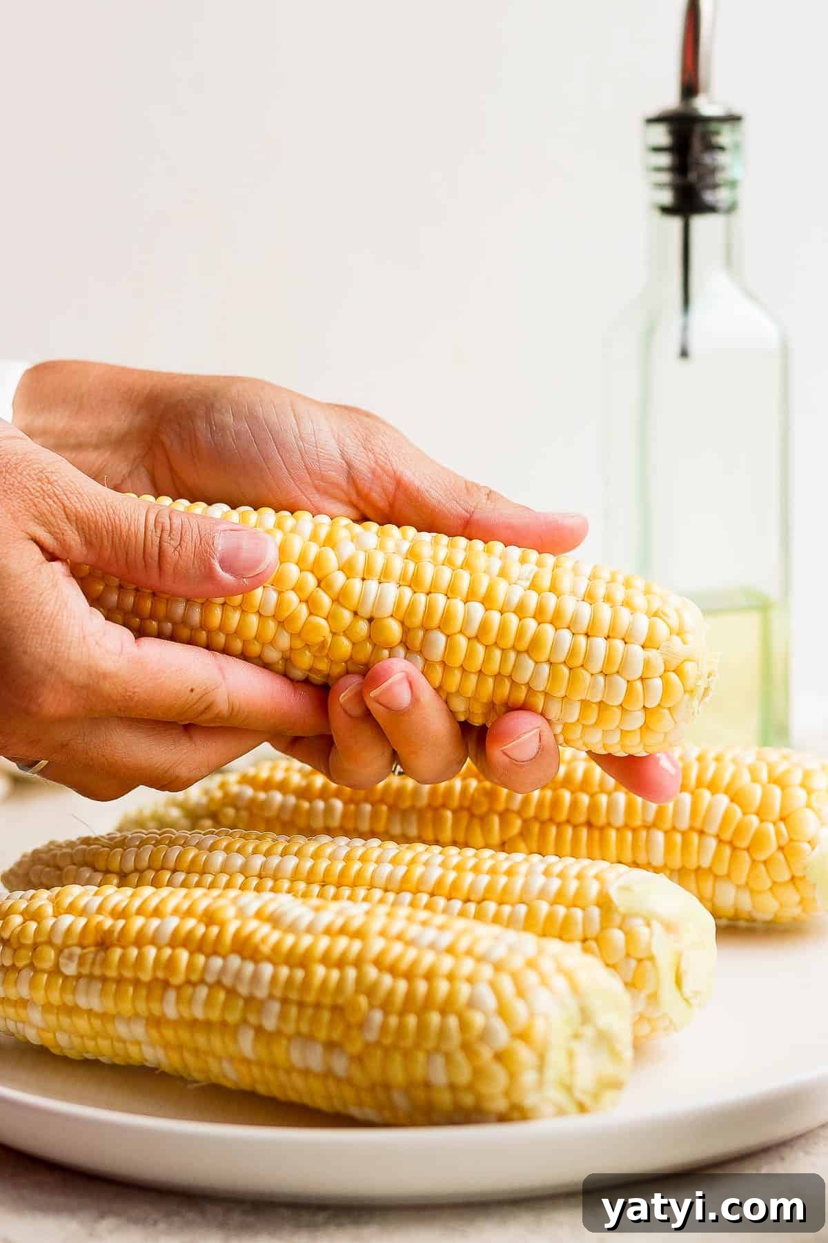 Ultimate Smoked Corn on the Cob Recipe for Sweet, Smoky Flavor 4 Someone rubbing oil on one ear of corn.