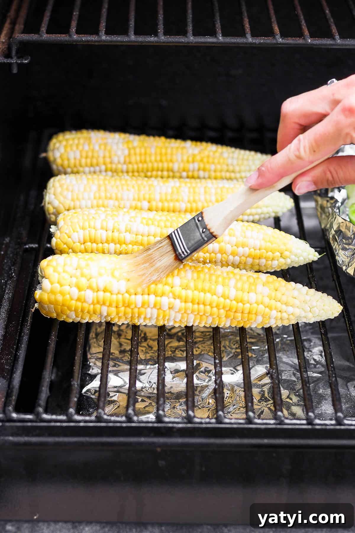 Ultimate Smoked Corn on the Cob Recipe for Sweet, Smoky Flavor 7 Smoked corn on the cob on the smoker being basted in butter.