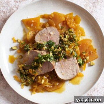 Pork Tenderloin with Roasted Golden Beets and Apricot-Mint Sauce 5 Sliced pork tenderloin atop golden beets and onions with an apricot-mint sauce on top on a white plate.