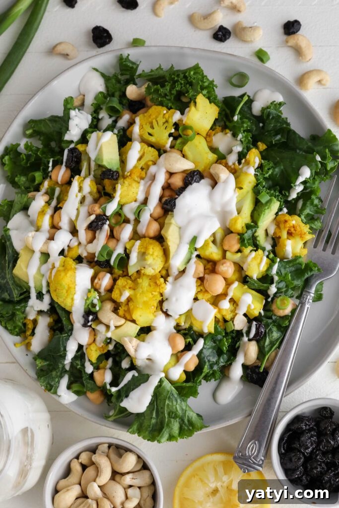 Curried Cauliflower and Kale Salad with Lemon-Tahini Dressing 2 Curried Cauliflower Kale Salad served on a plate drizzled with Yogurt Tahini surrounded by cashews, spring onion, and dried cranberries by Flora & Vino
