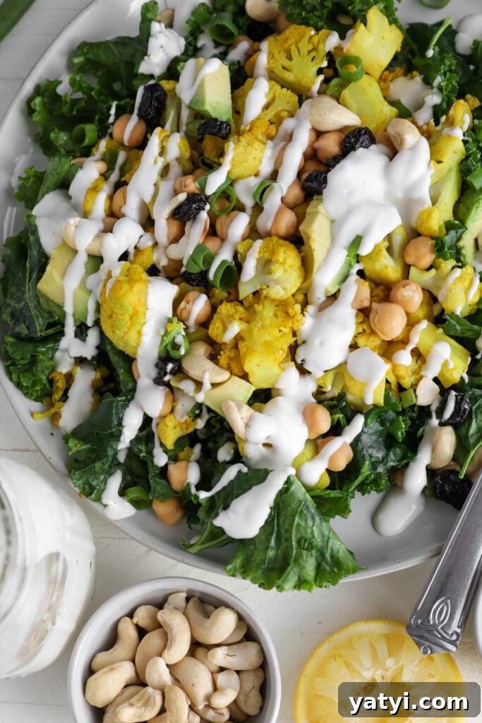 Curried Cauliflower and Kale Salad with Lemon-Tahini Dressing 10 Curried Cauliflower Kale Salad served on a plate drizzled with Yogurt Tahini surrounded by cashews, spring onion, and dried cranberries by Flora & Vino