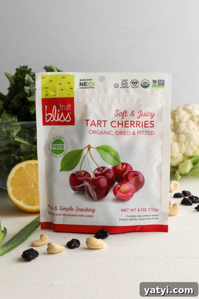 Curried Cauliflower and Kale Salad with Lemon-Tahini Dressing 3 Fruit Bliss Tart Cherries in packaging surrounded by lemon, cauliflower, kale, cashews, green onion, and dried cranberries by Flora & Vino
