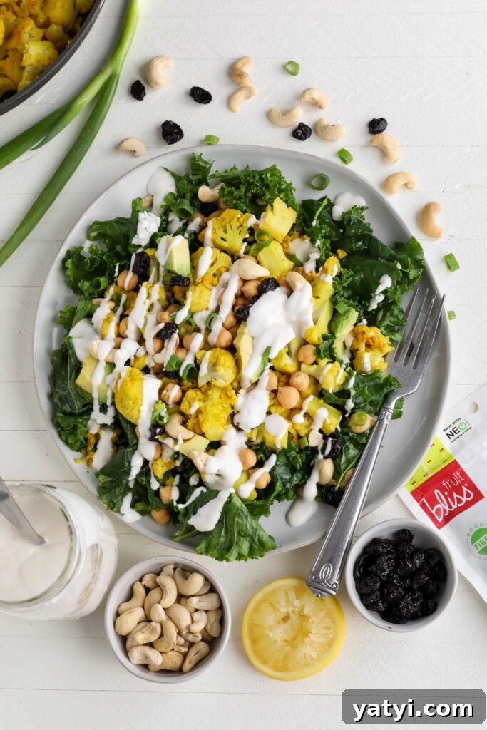 Curried Cauliflower and Kale Salad with Lemon-Tahini Dressing 8 Curried Cauliflower Kale Salad served on a plate drizzled with Yogurt Tahini surrounded by cashews, spring onion, and dried cranberries by Flora & Vino