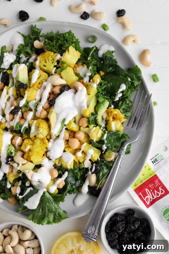 Curried Cauliflower and Kale Salad with Lemon-Tahini Dressing 9 Curried Cauliflower Kale Salad served on a plate drizzled with Yogurt Tahini surrounded by cashews, spring onion, and dried cranberries by Flora & Vino
