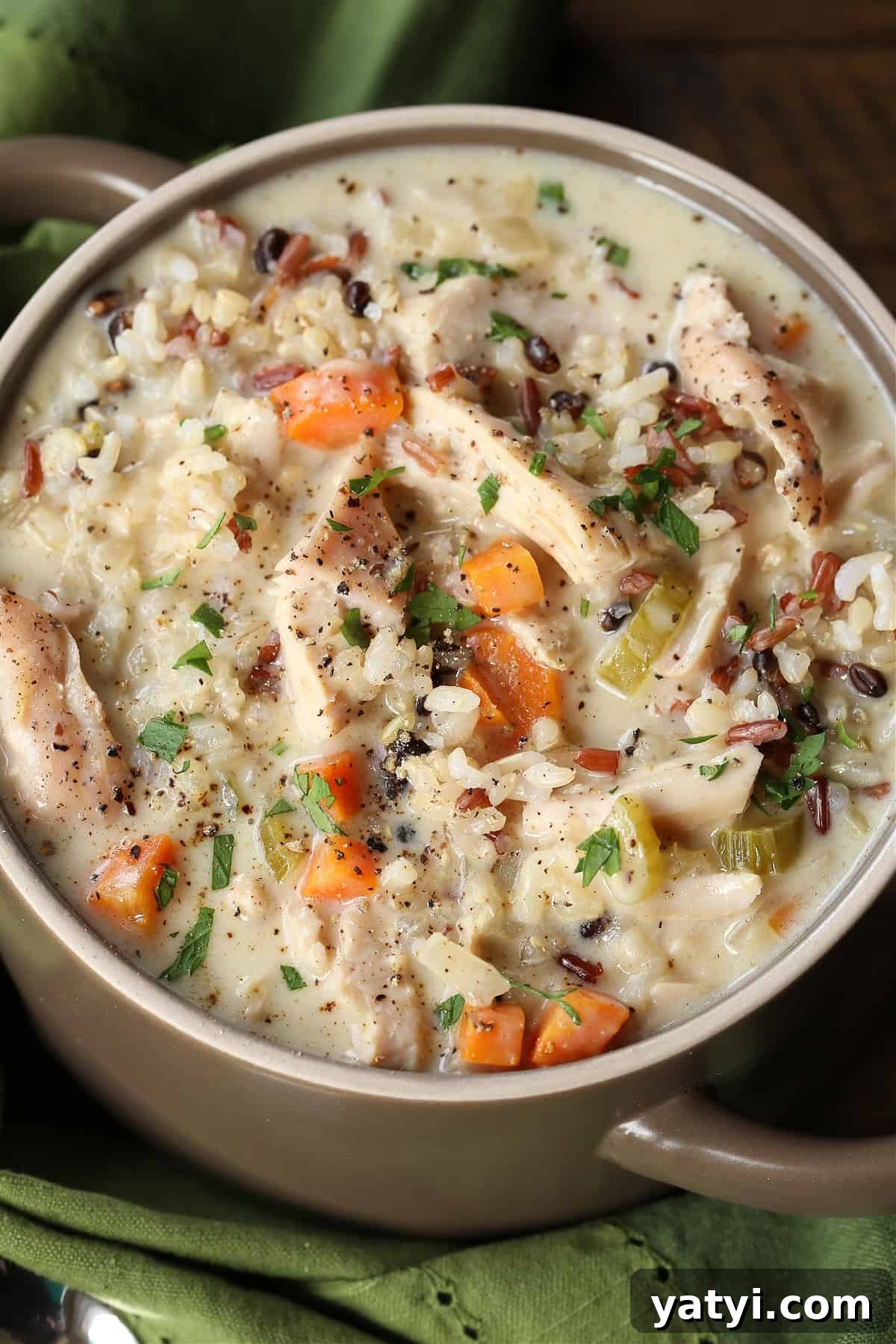 Our Turkey Wild Rice Soup is cozy and comforting: tender turkey with rice and vegetables in a smooth, sherry-infused broth. turkey and rice soup in a crock with green napkin