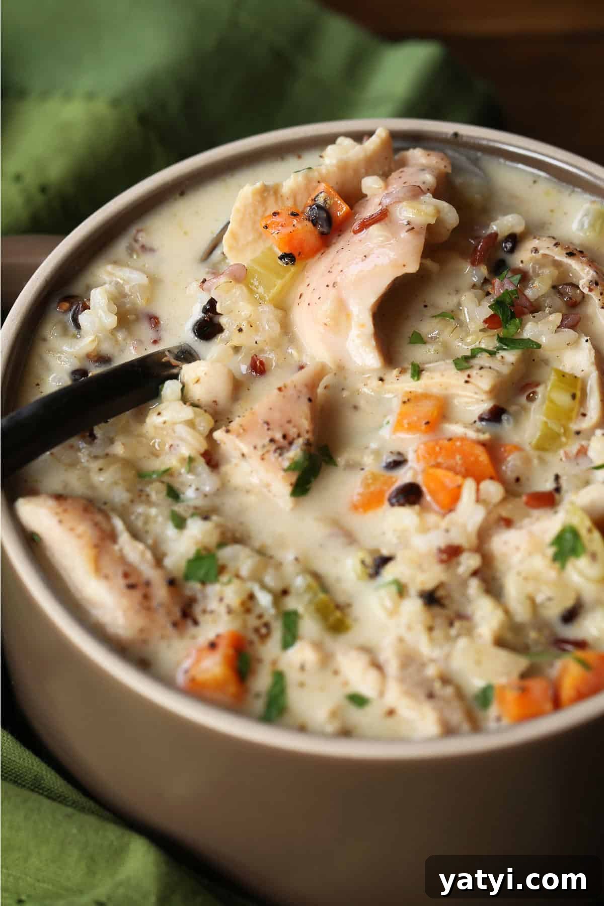 Our Turkey Wild Rice Soup is cozy and comforting: tender turkey with rice and vegetables in a smooth, sherry-infused broth. spoon in bowl of turkey soup with rice and vegetables