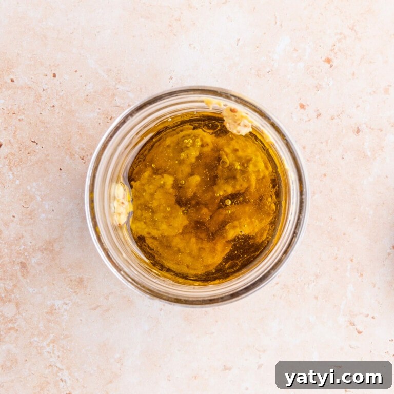 Adding olive oil, apple cider vinegar, maple syrup and Dijon mustard to a glass jar