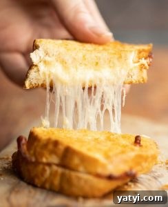 Air Fryer Grilled Cheese close up shot of hand pulling up half of grilled cheese with cheese dripping out